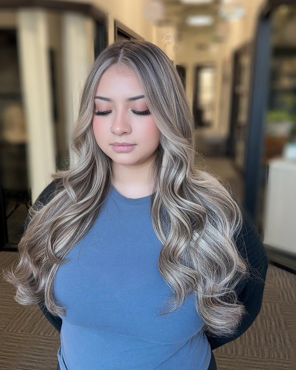 Woman with long, curled ash-blonde hair and delicate silvery highlights