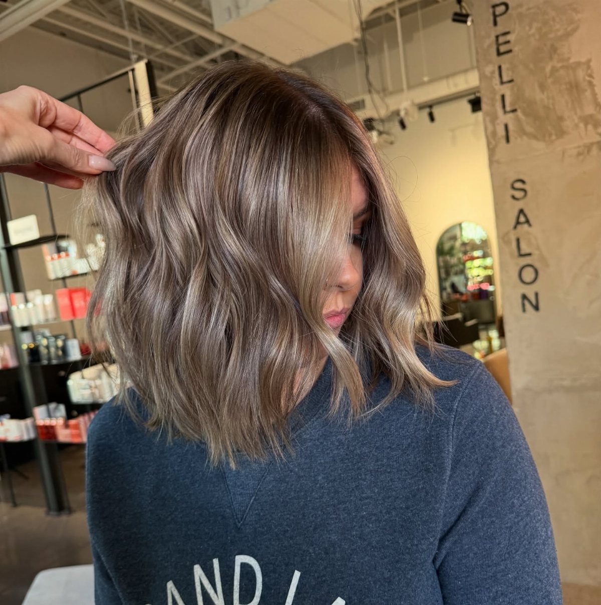 Shoulder-length brown hair blends into beige and blonde highlights in a salon
