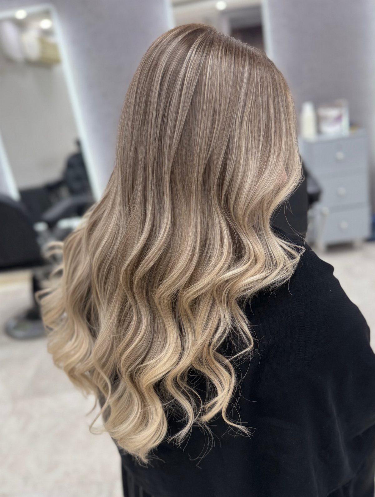 Long wavy blonde hair with soft beige highlights and darker roots