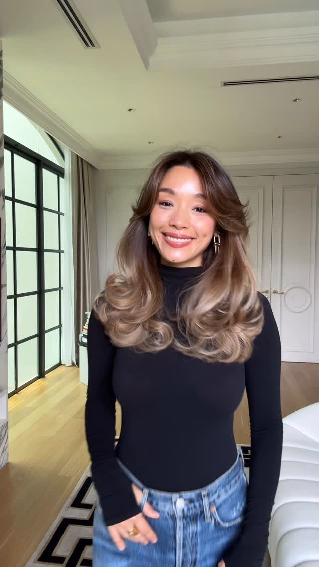 Woman posing with long, wavy balayaged brown hair and blonde ends