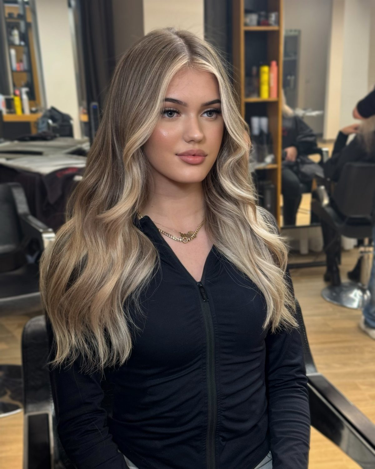 Woman with long wavy brown hair and ash-blonde highlights in a salon