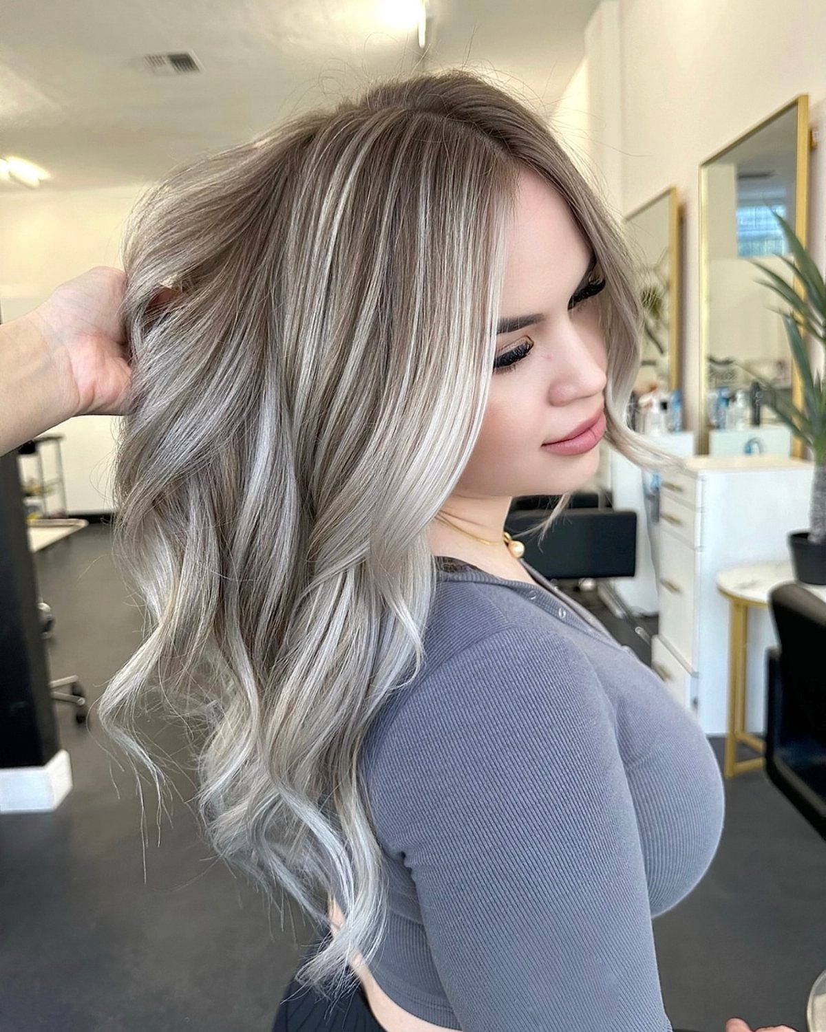 Woman showing long, wavy ash blonde hair with fine highlights in a salon