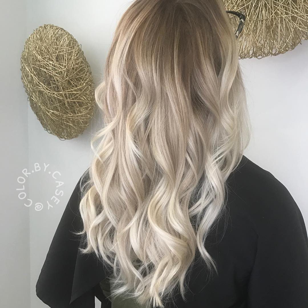 Long ash-blonde curls with darker roots and silver face-framing strands