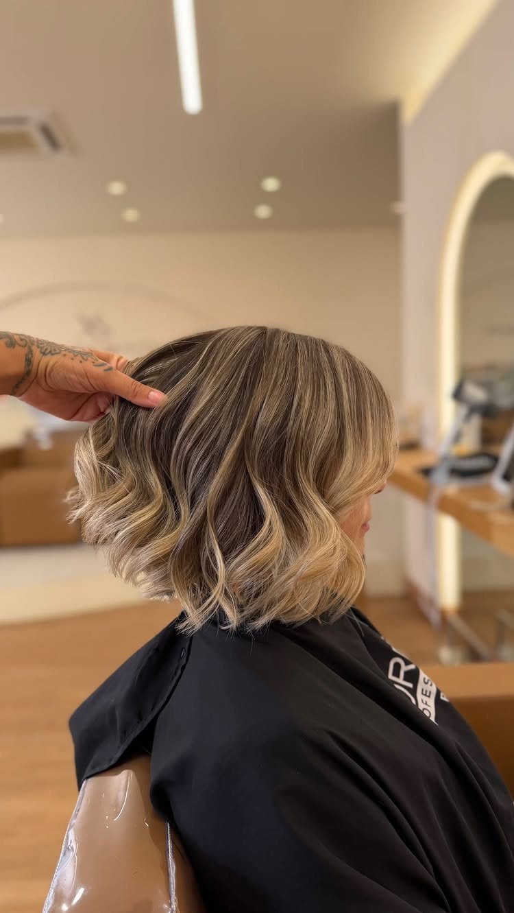 Wavy blonde bob with dark roots and fine highlights in a salon