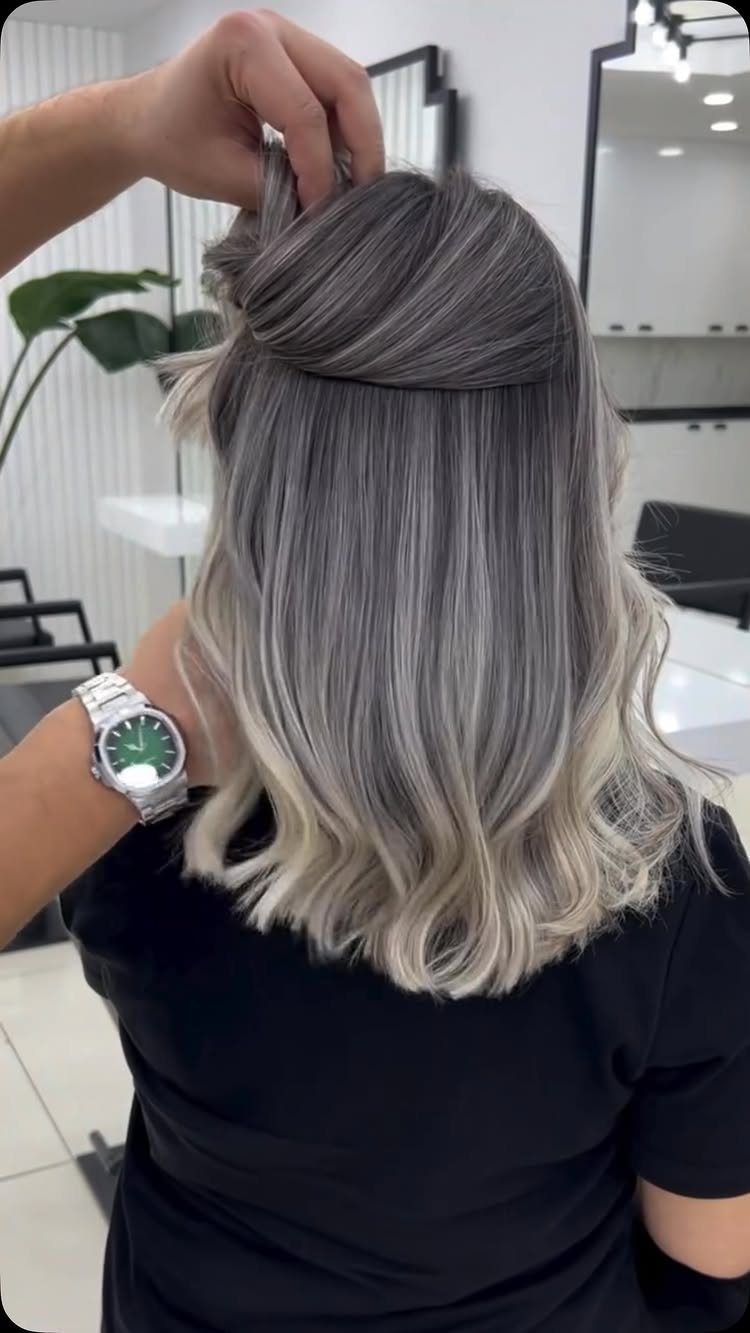 Ash blonde babylights with silver-gray dimension and softly waved ends in a salon