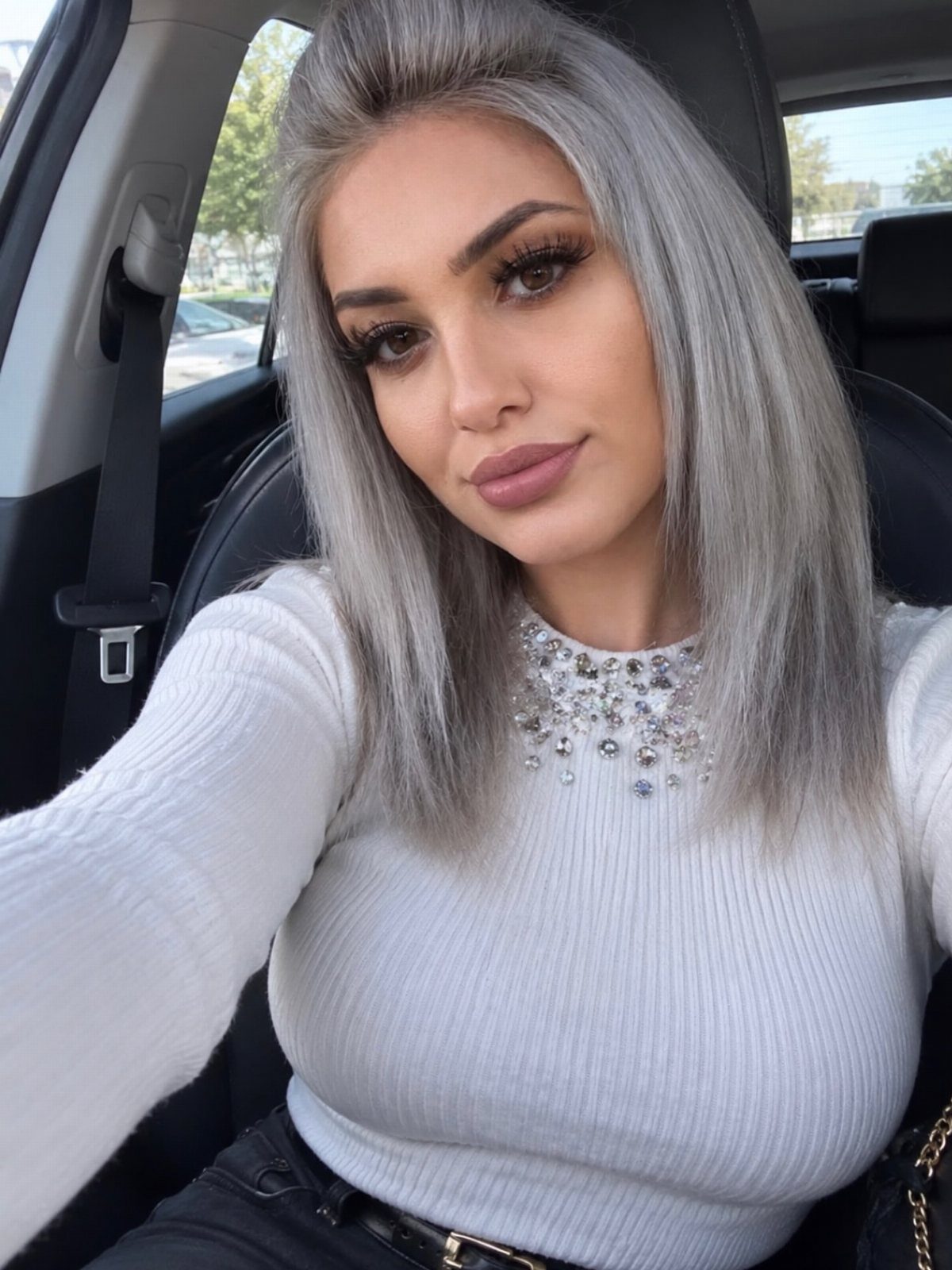 Woman with straight silver-blonde hair and bright front pieces seated in a car