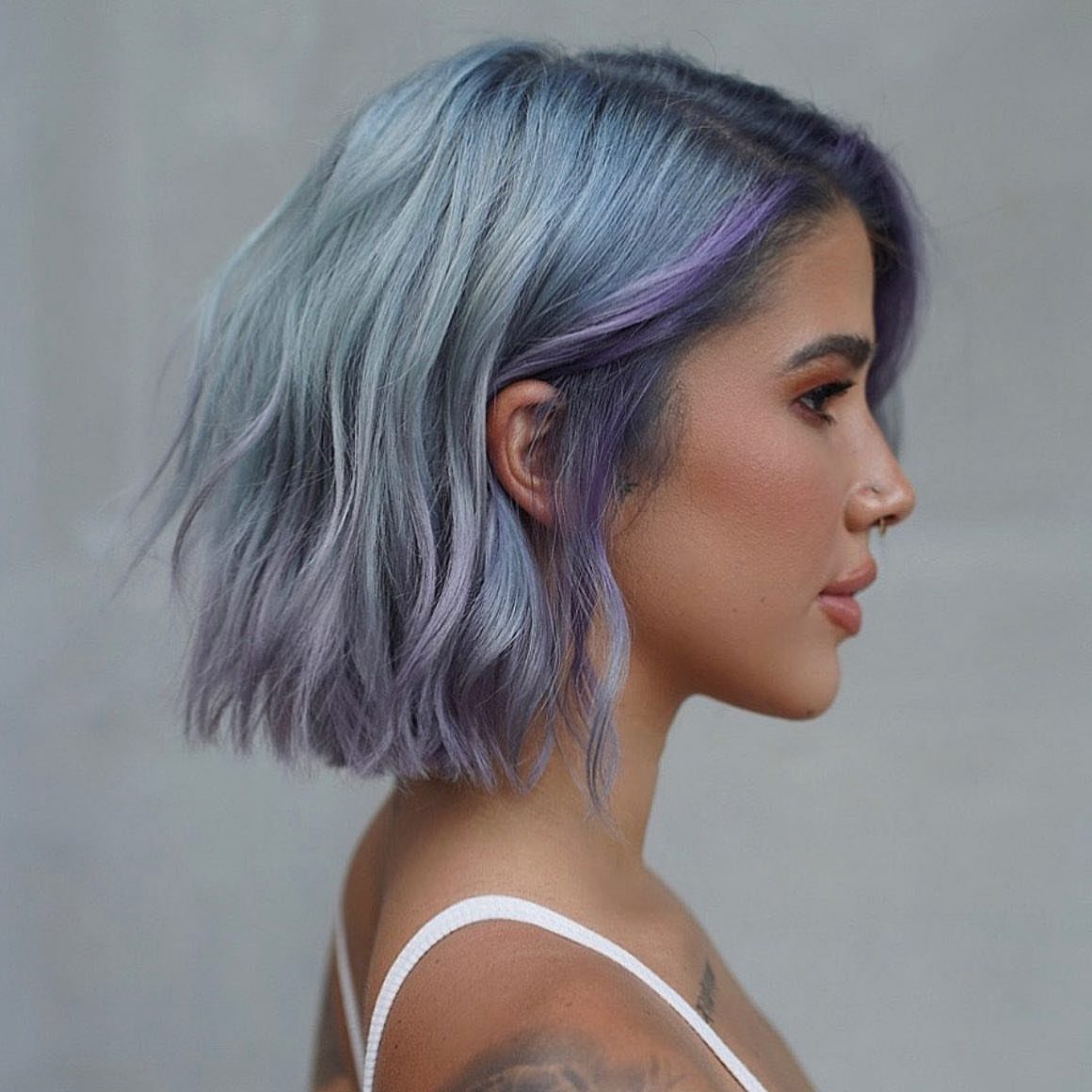 Woman with a wavy silvery-lavender bob and darker roots in profile