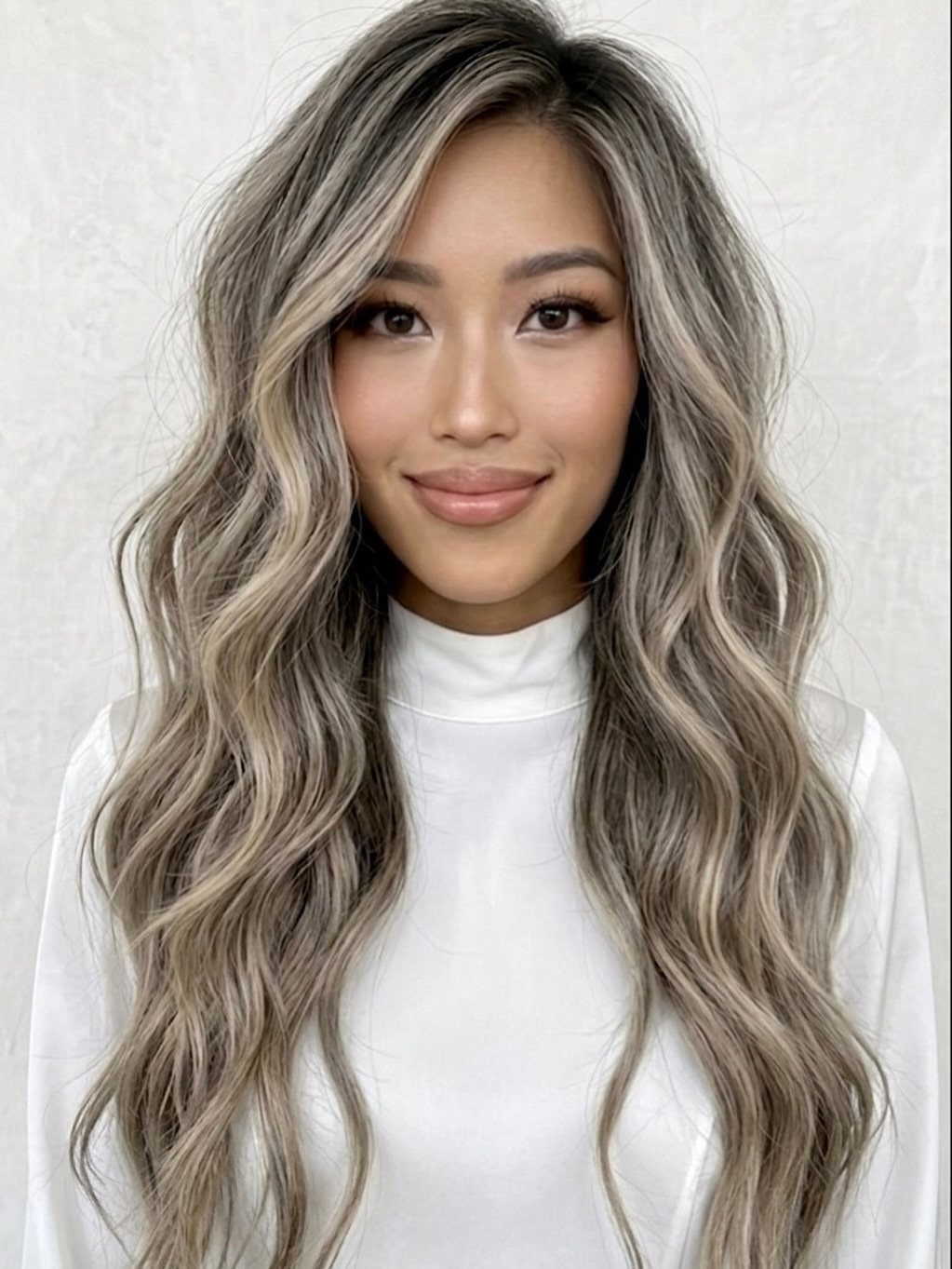 Woman with long wavy smoky ash-blonde hair and dark roots
