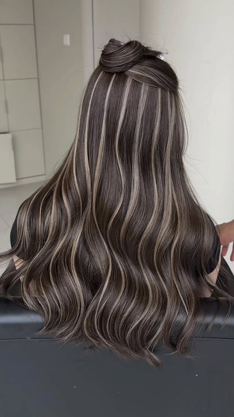 Long dark ash hair with distinct silver-gray streaks in loose waves