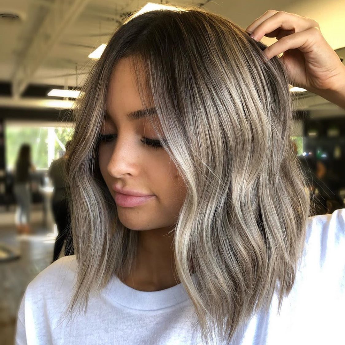 Wavy shoulder-length bob with silver and ash blonde highlights in a salon