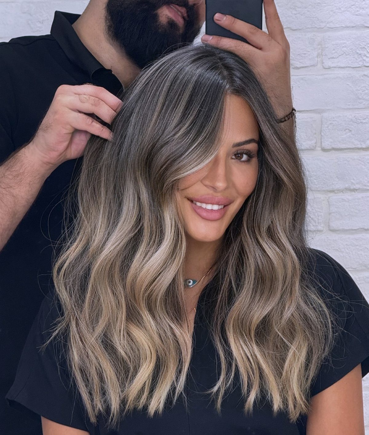 Woman with long wavy dark hair and cool ash-blonde highlights