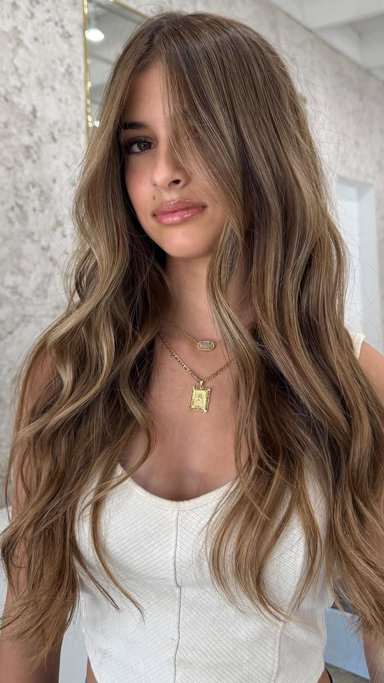 Woman with long brown hair and blonde face-framing highlights