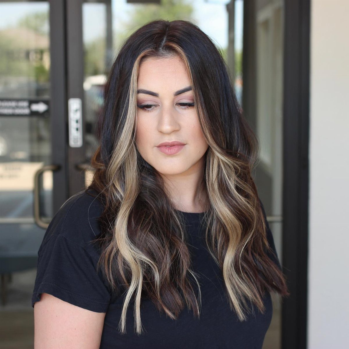Woman with dark wavy hair and blonde face-framing highlights