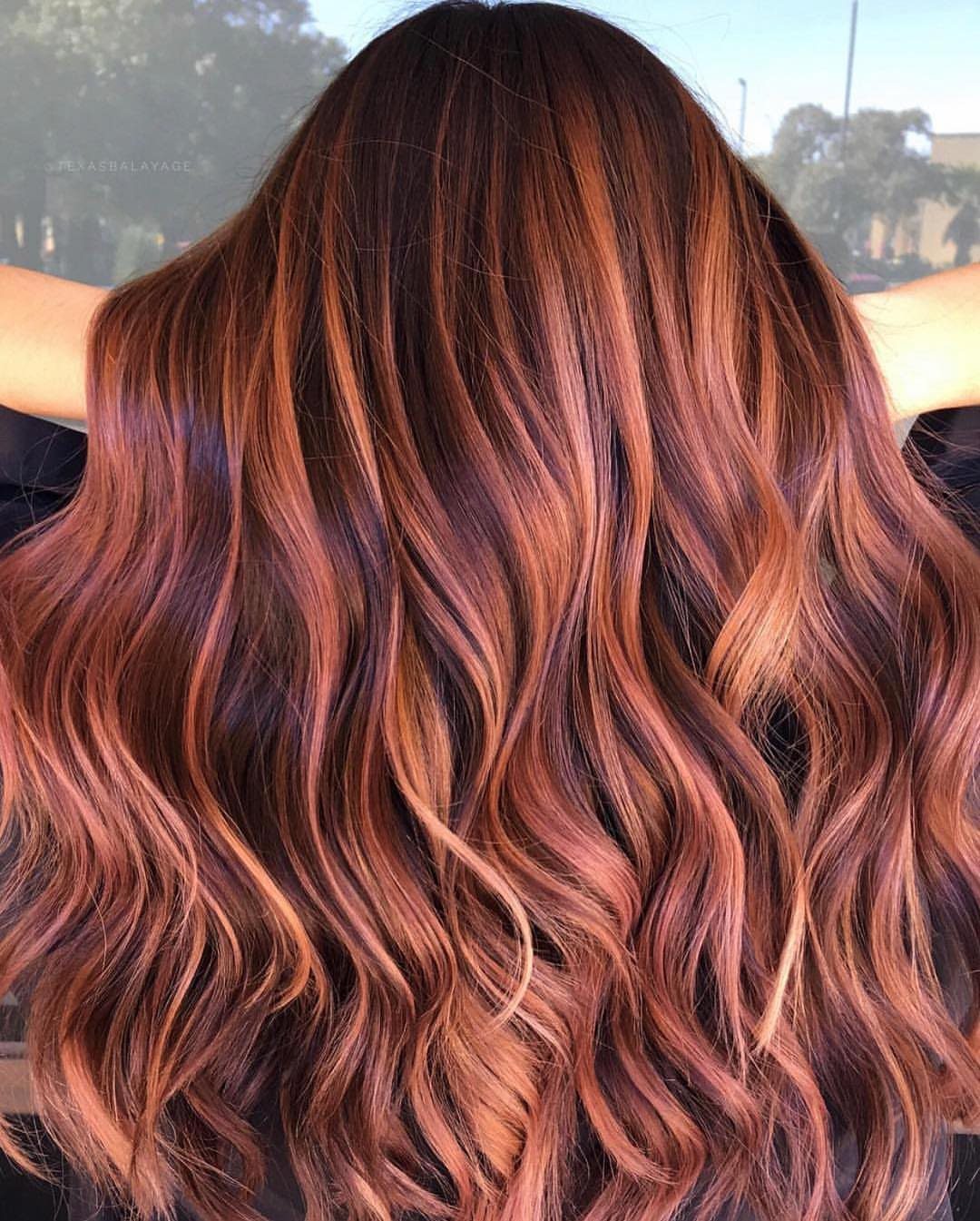 Long dark brown waves shimmer with rose-gold and copper highlights