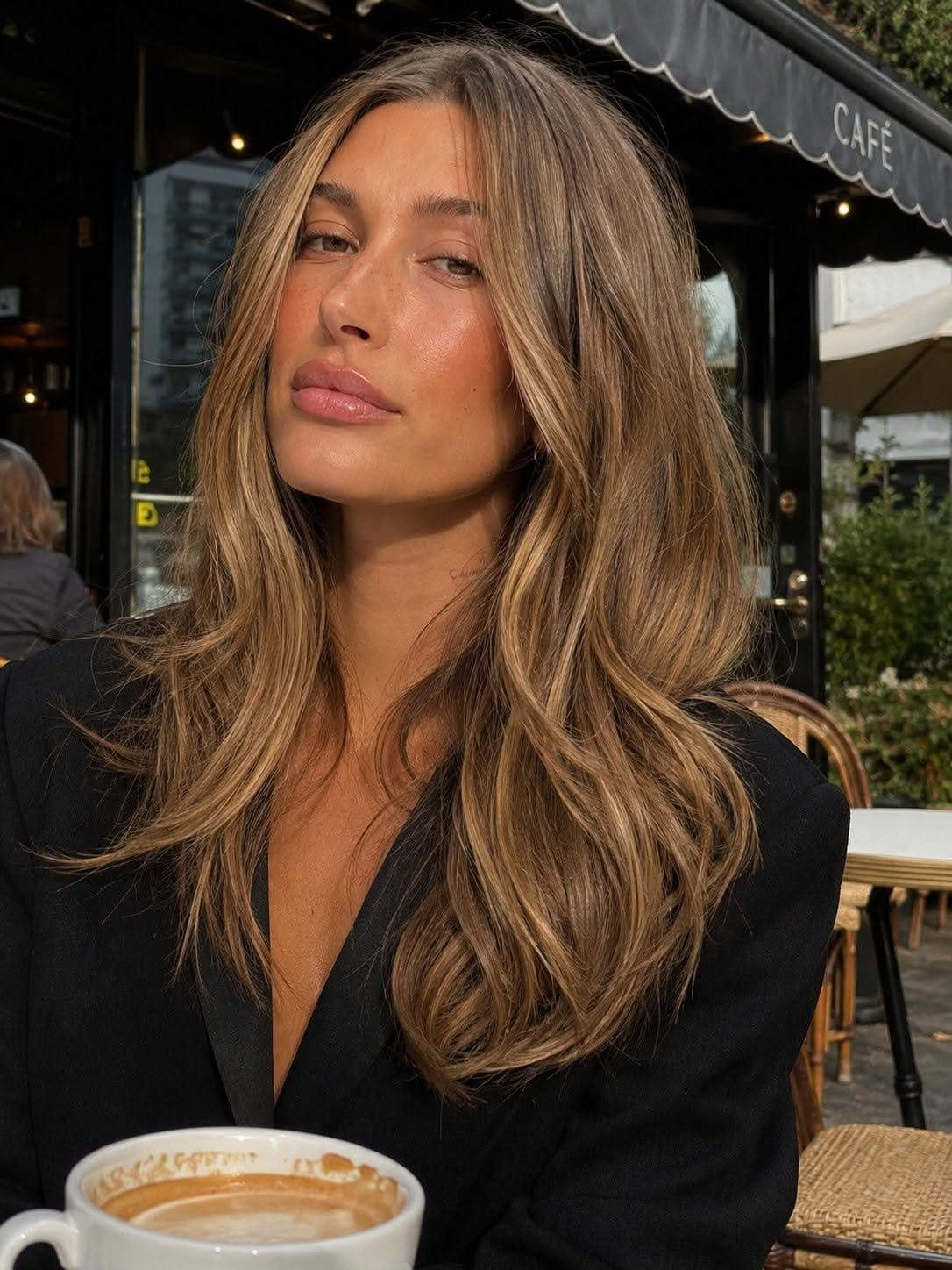 Woman showing cool blonde ribbons through long, wavy espresso-brown hair at a café