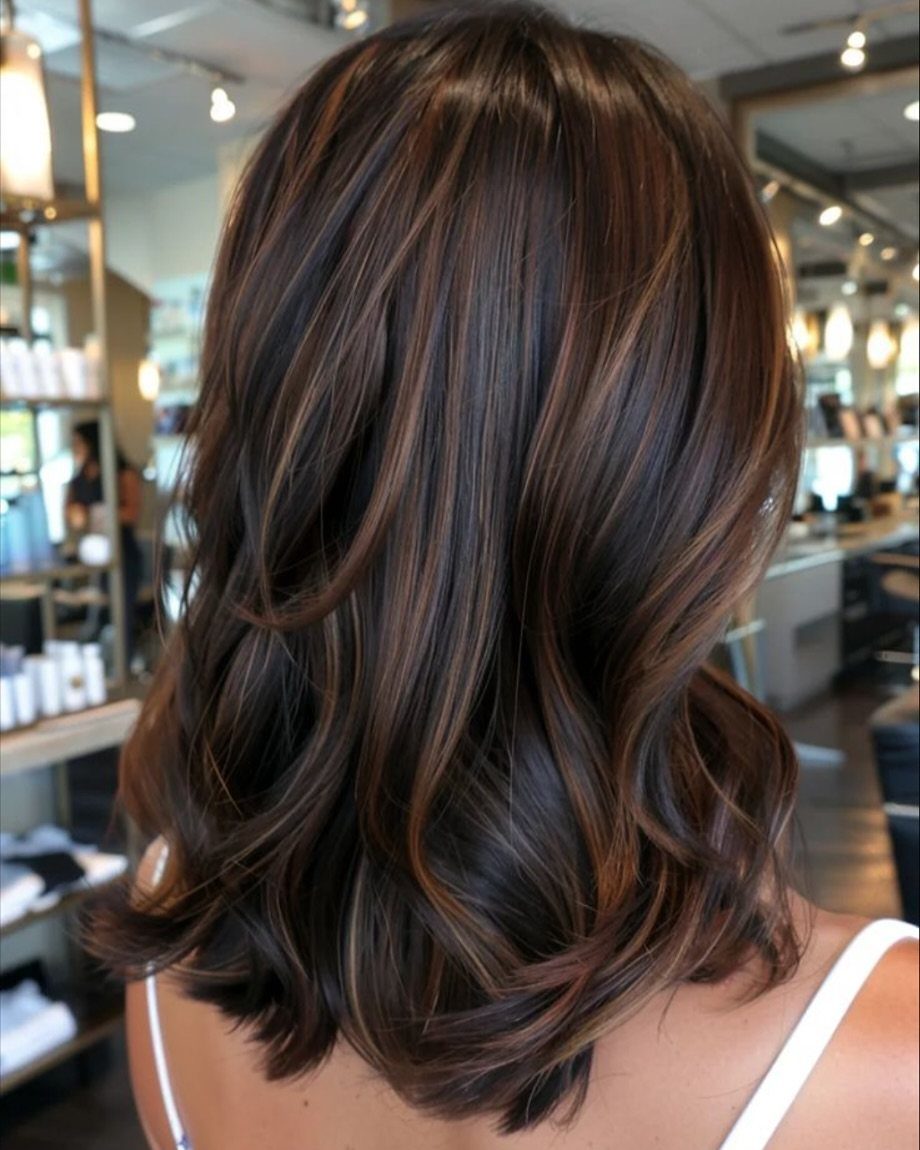 Dark brunette hair with warm brown highlights styled in loose curls