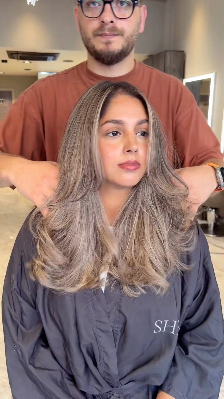 Woman showing long beige-blonde balayage hair in a salon chair