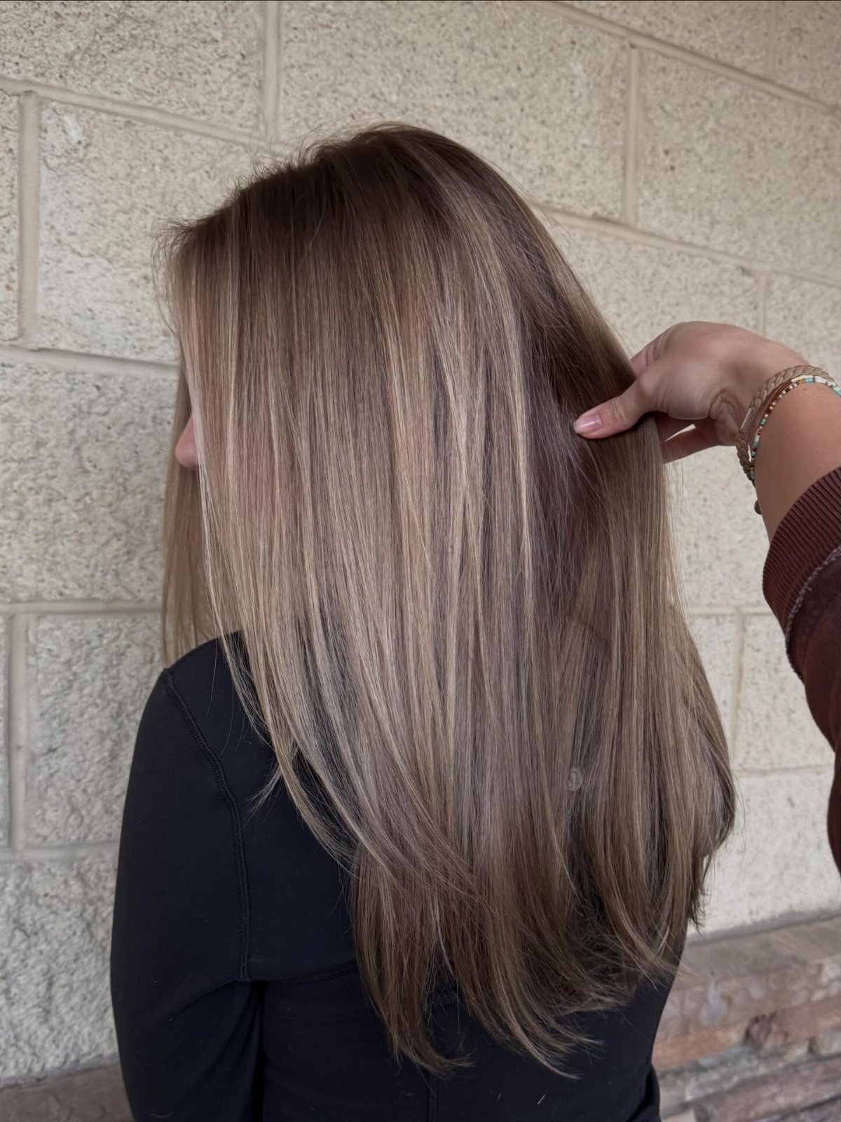 Long dirty blonde balayage hair with cool lighter strands and darker roots