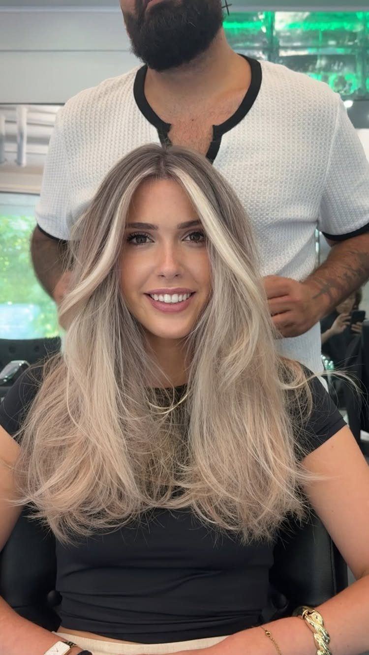 Woman displaying long dirty blonde ombré hair with darker roots and brighter lengths