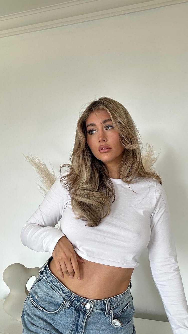 Woman with wavy dirty blonde hair and lighter face-framing balayage