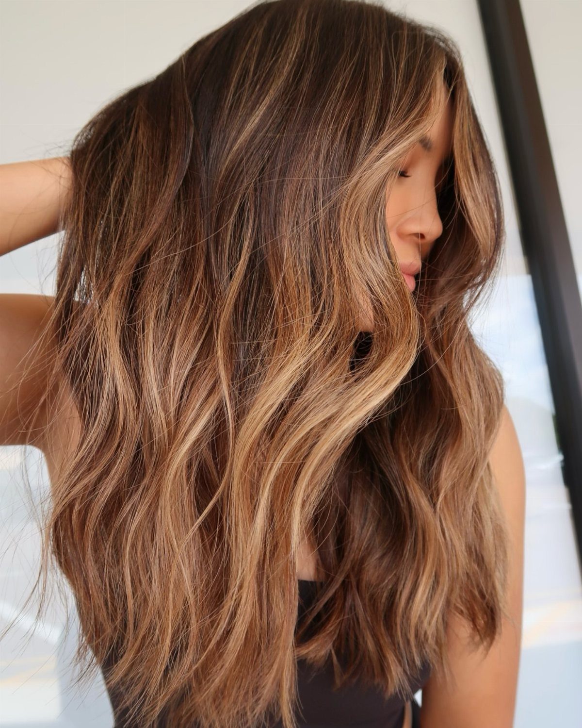 Long wavy brunette hair with warm golden highlights and lighter ends