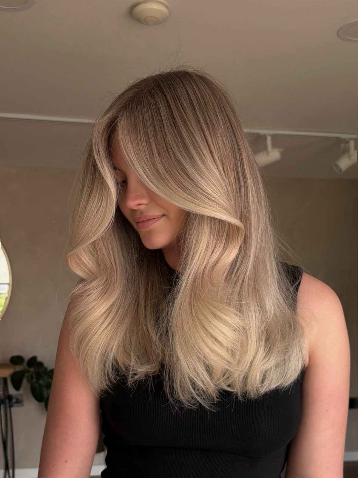Woman showing long blonde hair with subtle lighter balayage and soft waves