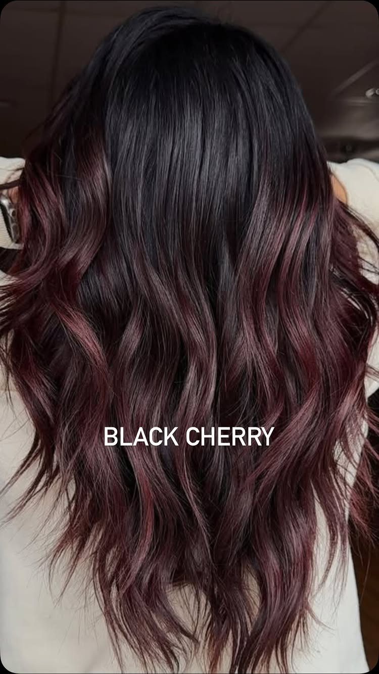Long black waves blend into burgundy-red balayage through the lengths and ends