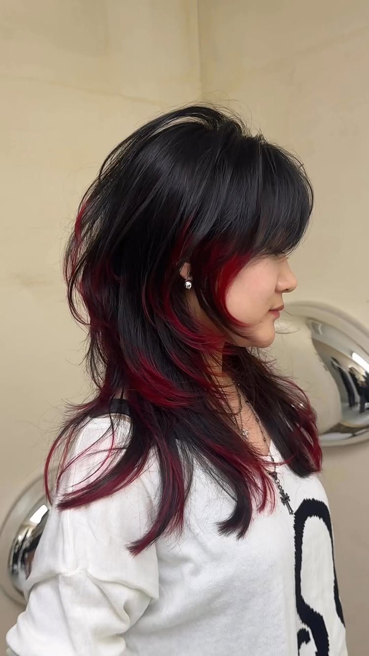 Long black layers reveal deep red underlights beneath the outer hair