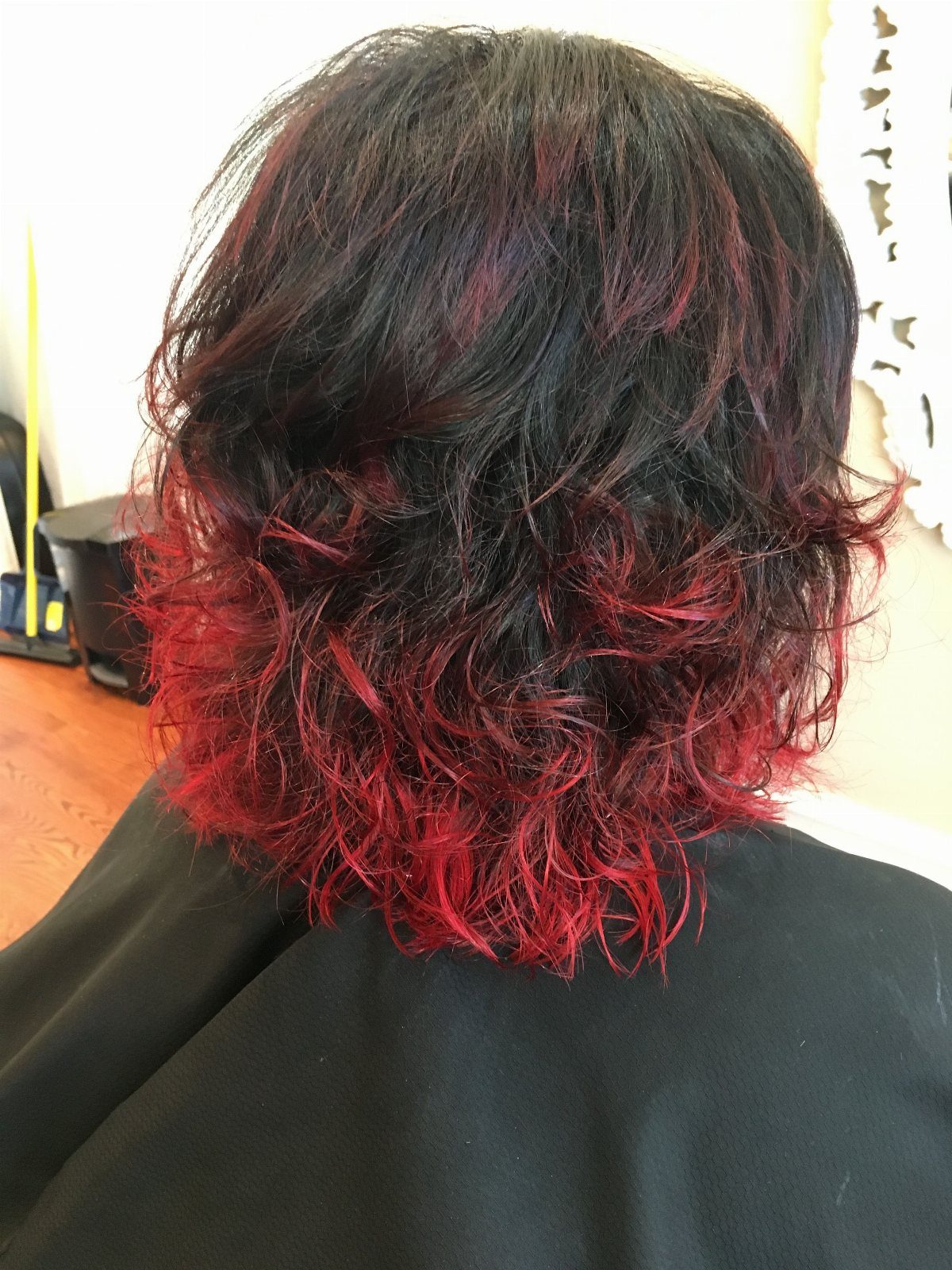 Layered black hair with vivid red color through the wavy ends