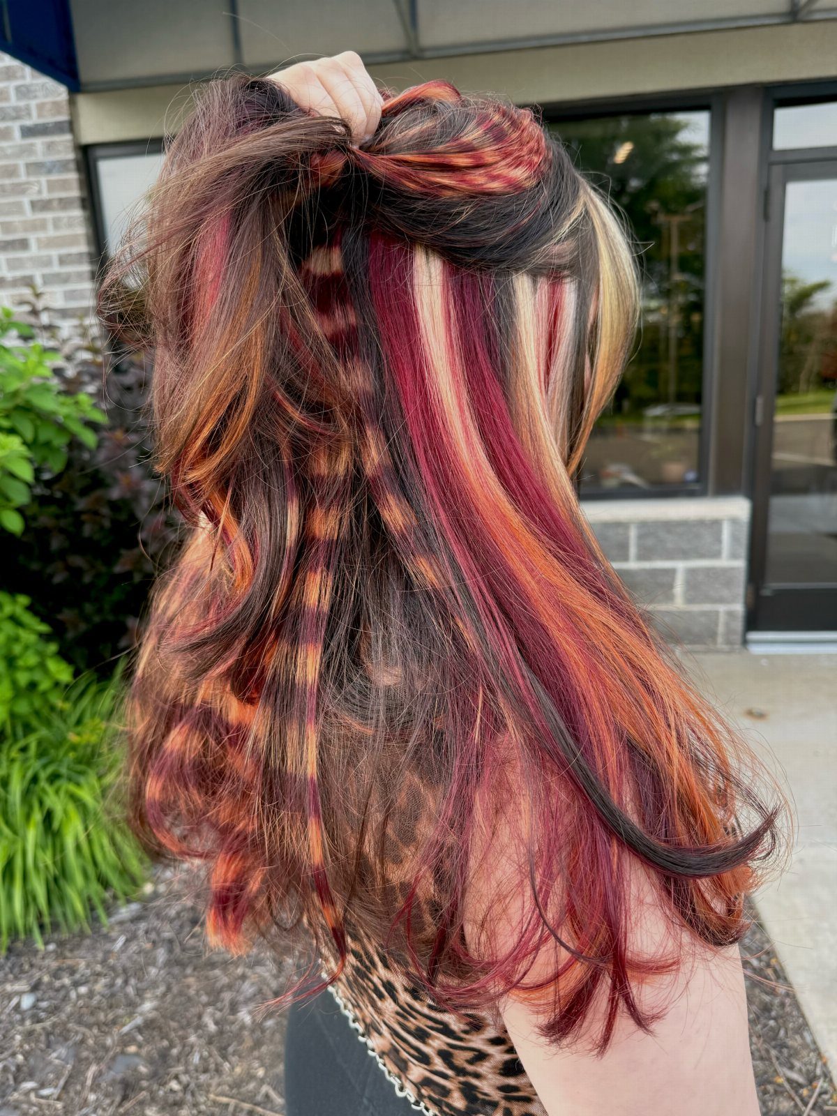 Long dark wavy hair with vivid burgundy and red striped highlights