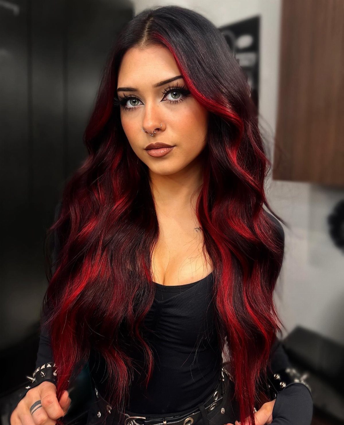 Woman with long black waves and vivid burgundy-red streaks throughout