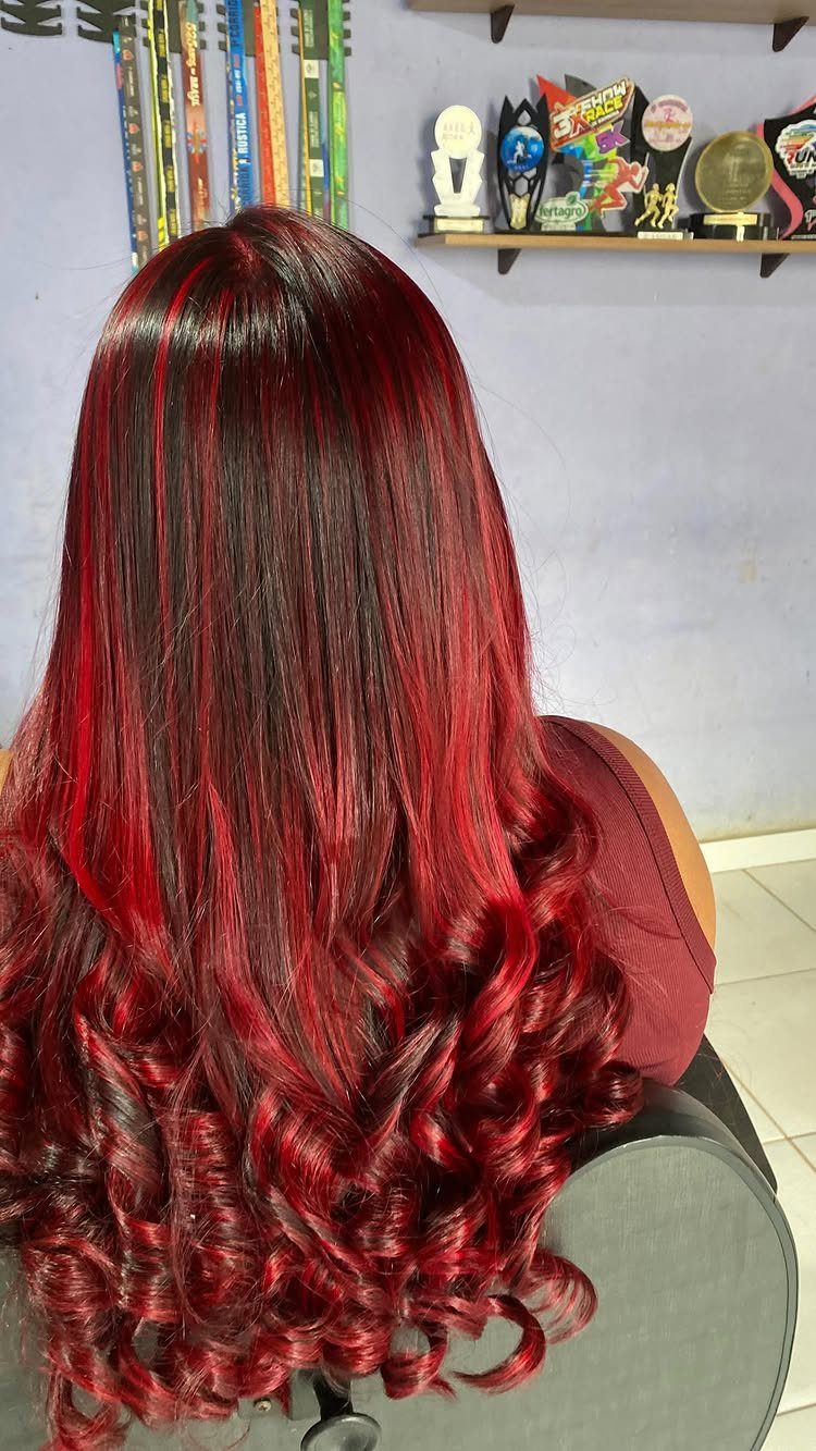 Long dark hair with vivid red streaks styled in glossy curls