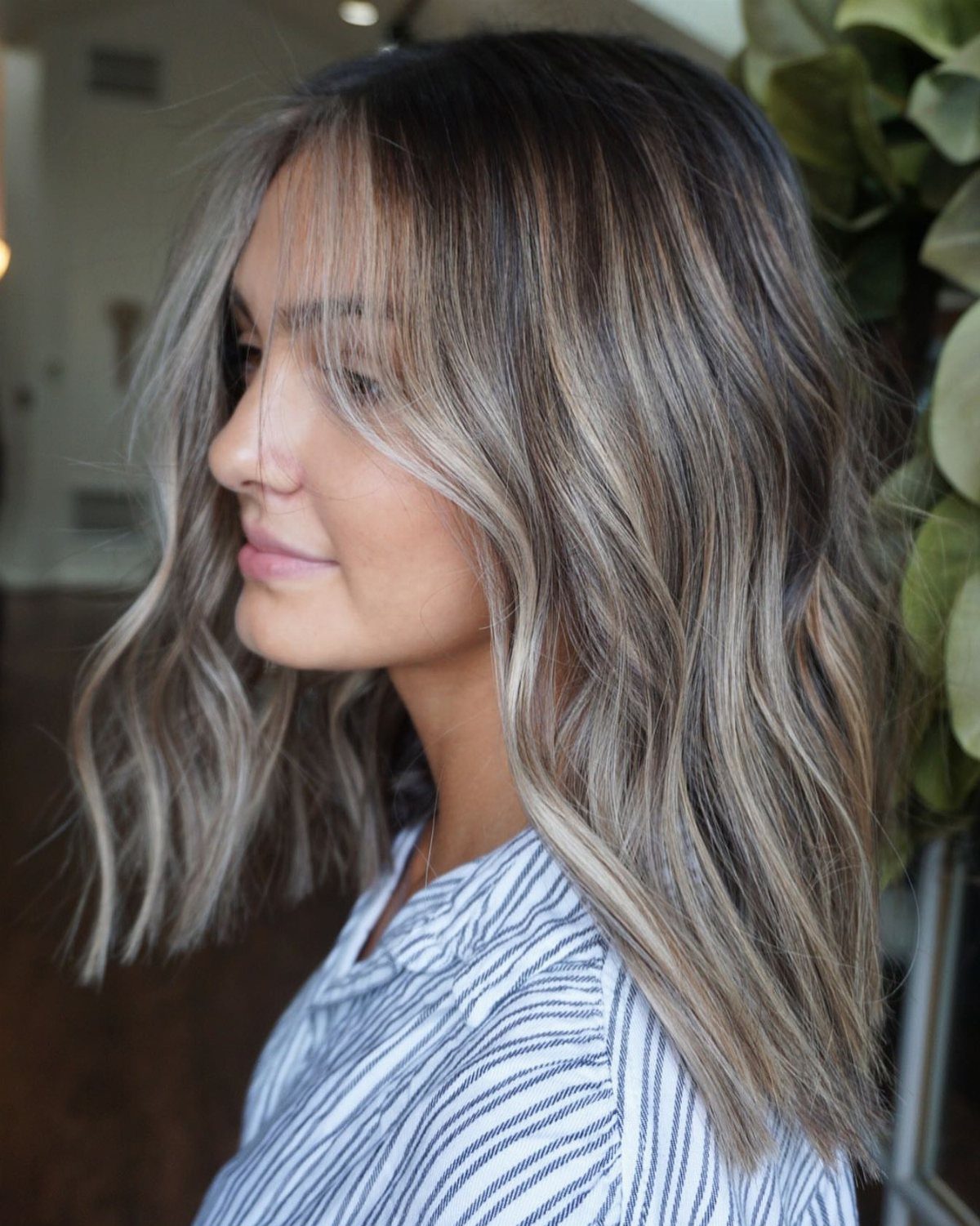 Woman with long wavy dark hair and cool ash balayage highlights