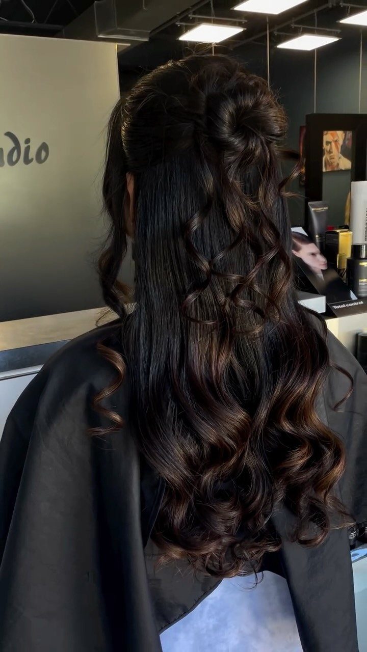 Long dark brown half-up ponytail with curled highlighted ends in a salon
