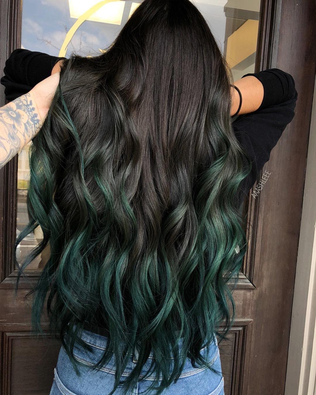 Long black waves blend into vivid teal-green balayage toward the ends