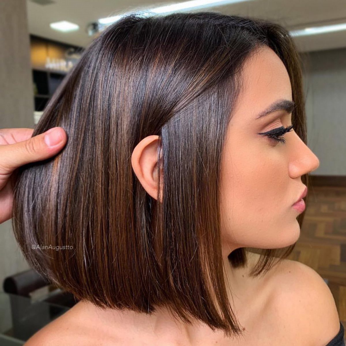Chin-length dark bob with subtle chestnut balayage highlights in a salon