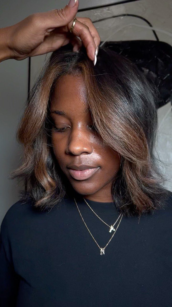Dark-haired woman with caramel balayage pieces framing her face