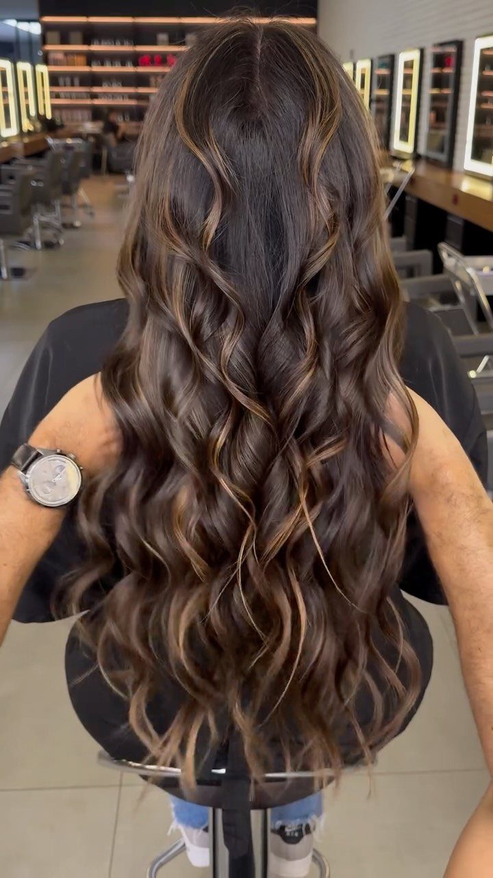Long dark chocolate hair with subtle highlights styled in glossy loose curls