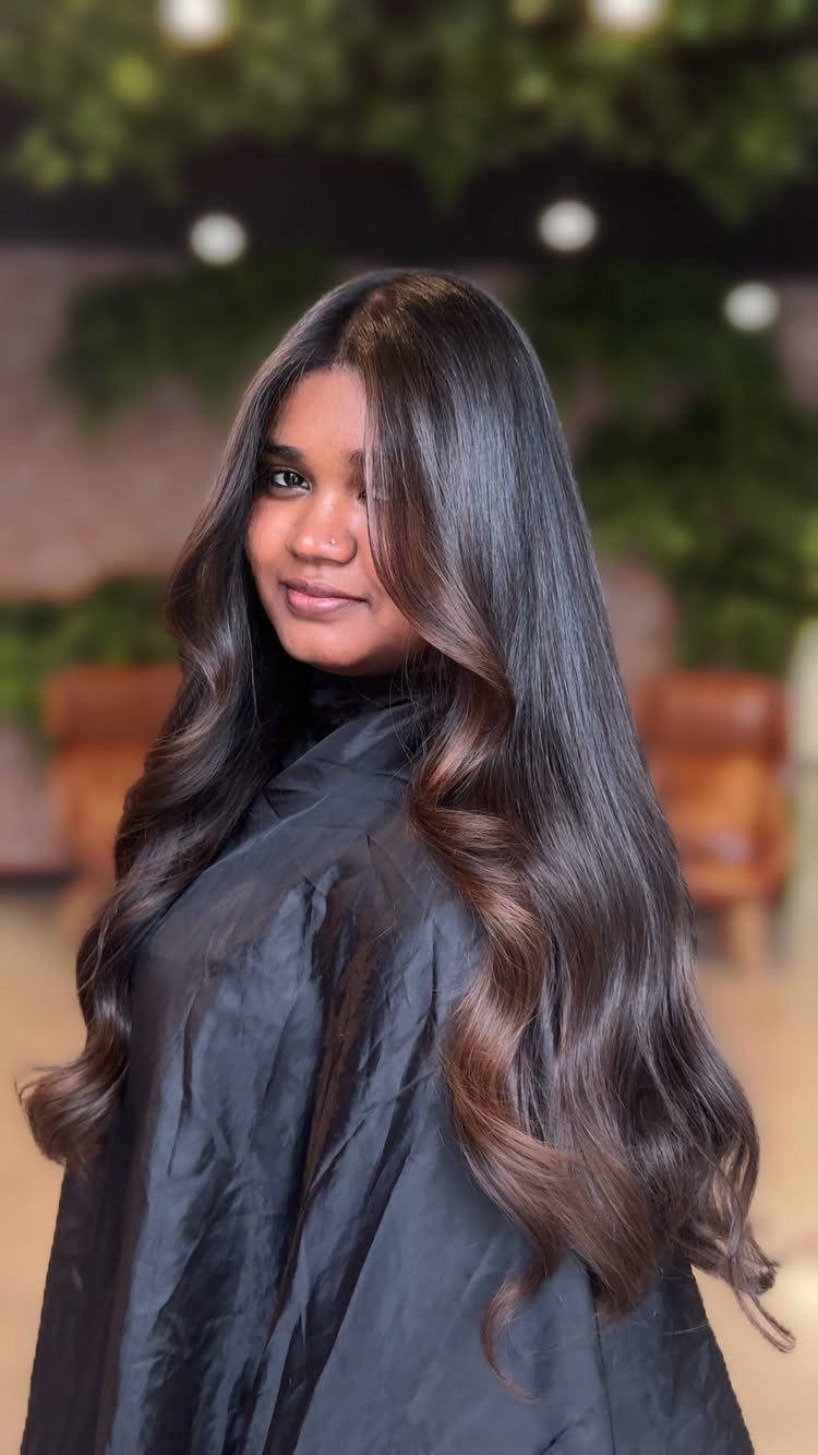 Woman with long dark brown waves and subtle hazelnut balayage highlights