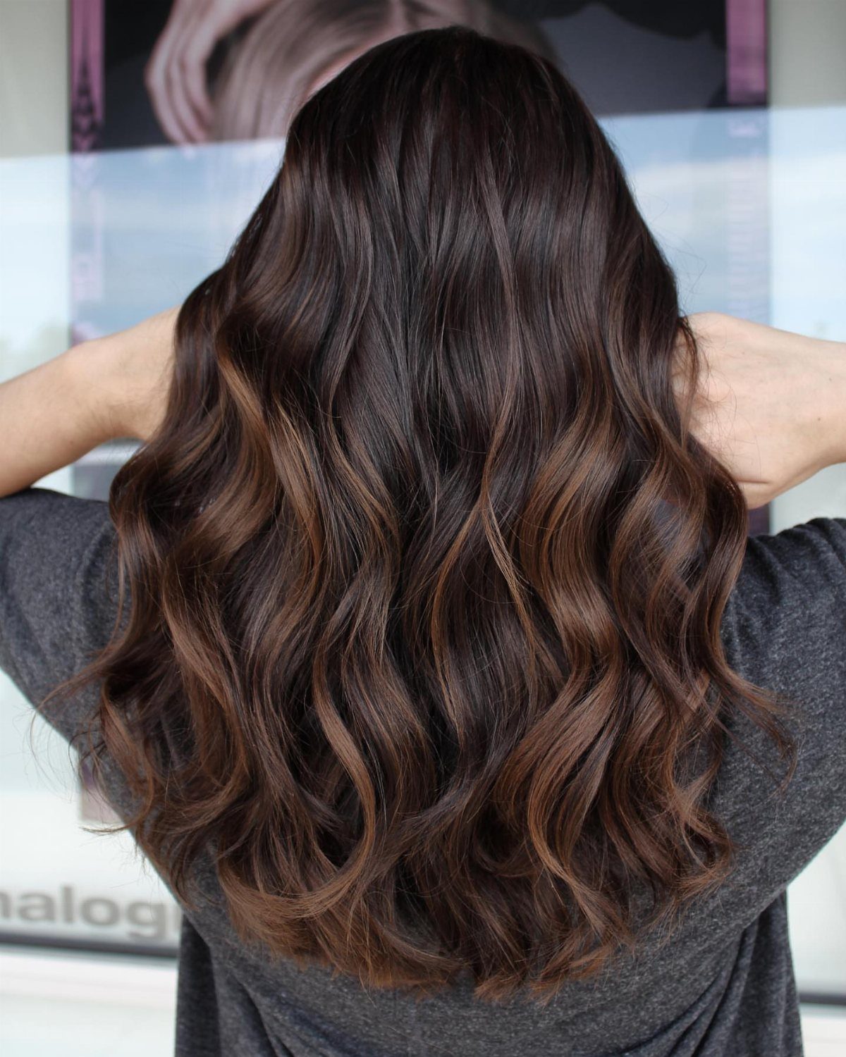 Long dark brown waves show understated muted highlights through the lengths