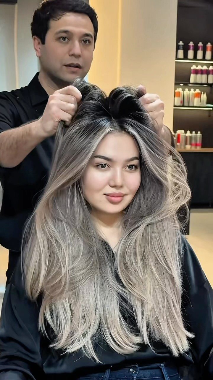 Woman displays long smoky beige balayage hair in a salon chair