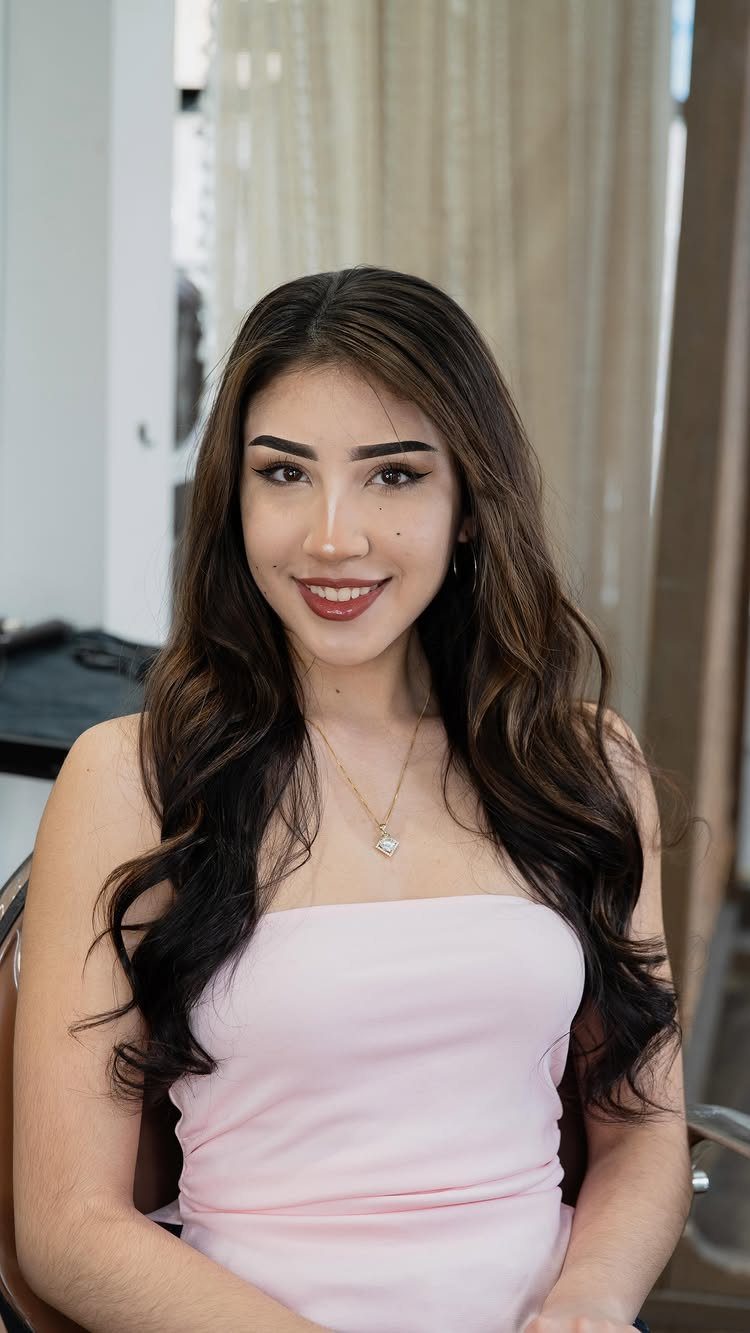 Woman with long, wavy dark brown hair and subtle lighter highlights