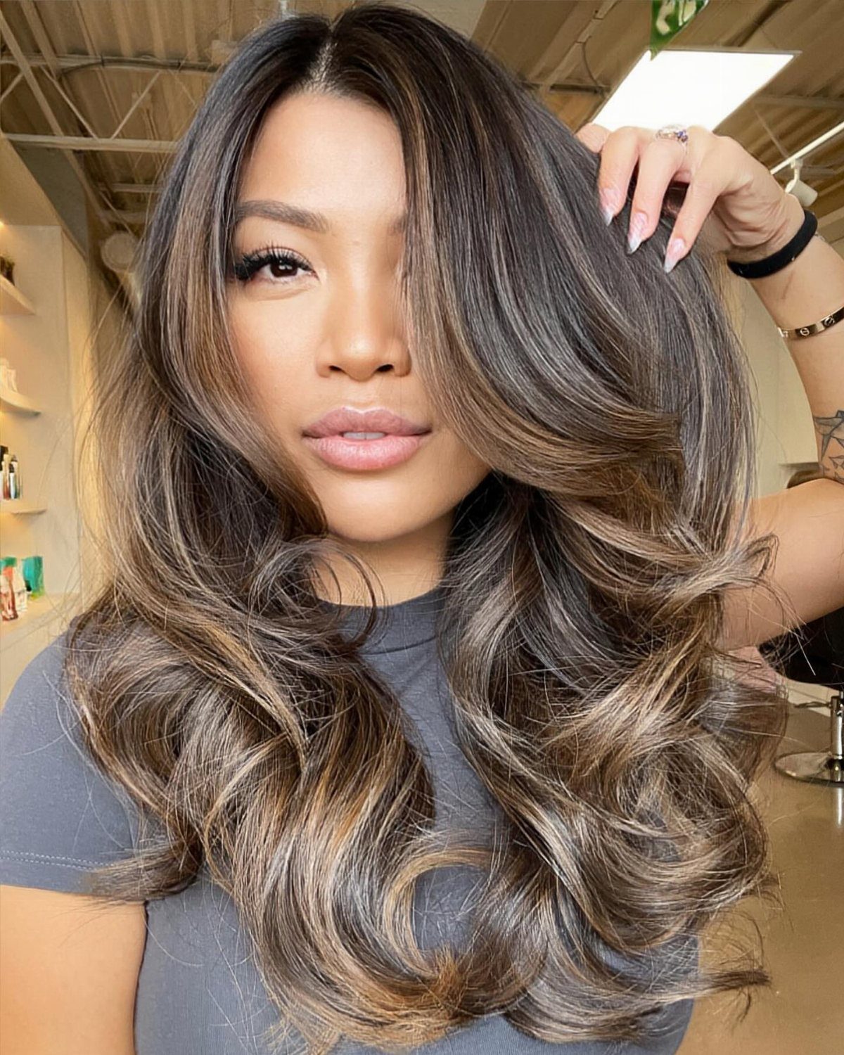 Woman showing long dark hair with radiant golden-brown balayage highlights