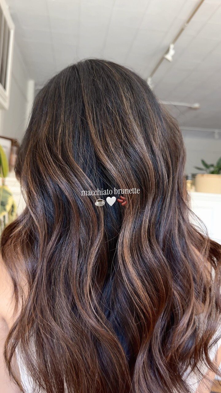 Long wavy dark hair with caramel balayage highlights in a salon