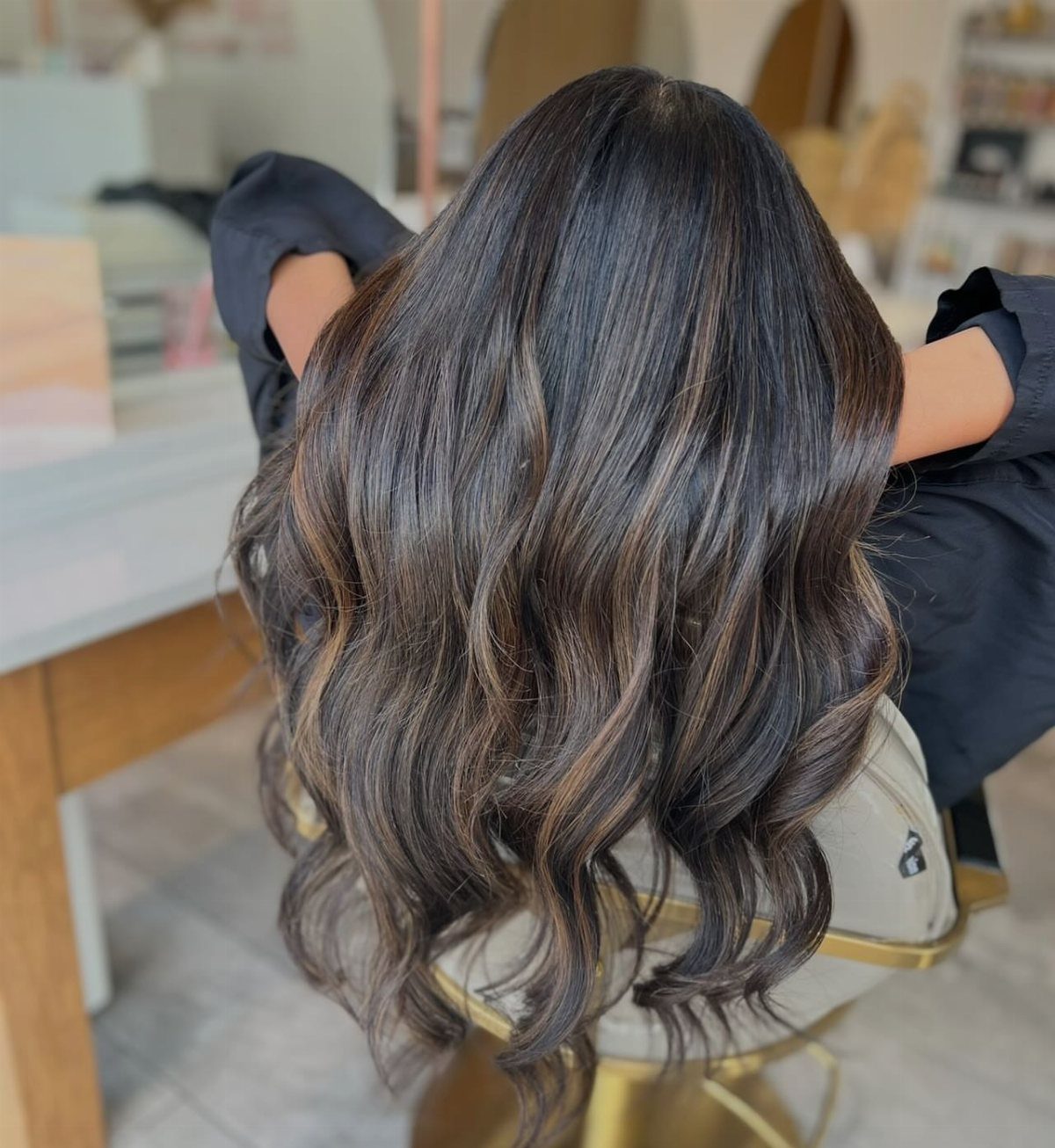 Long dark wavy hair with subtle warm cinnamon-brown highlights