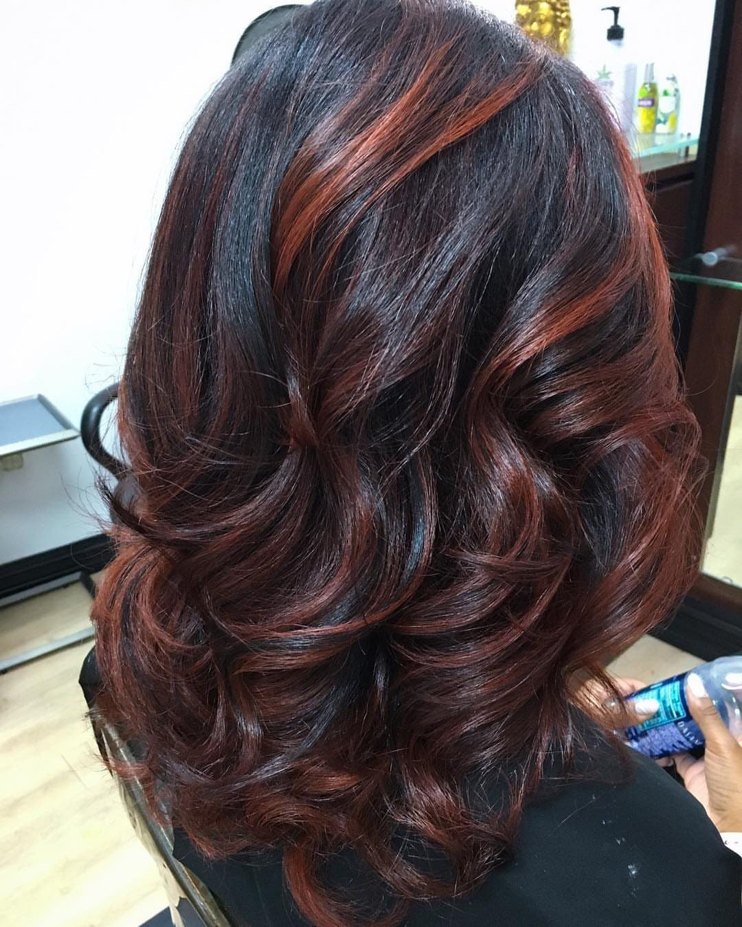 Dark layered hair with vivid copper highlights styled into glossy curled waves