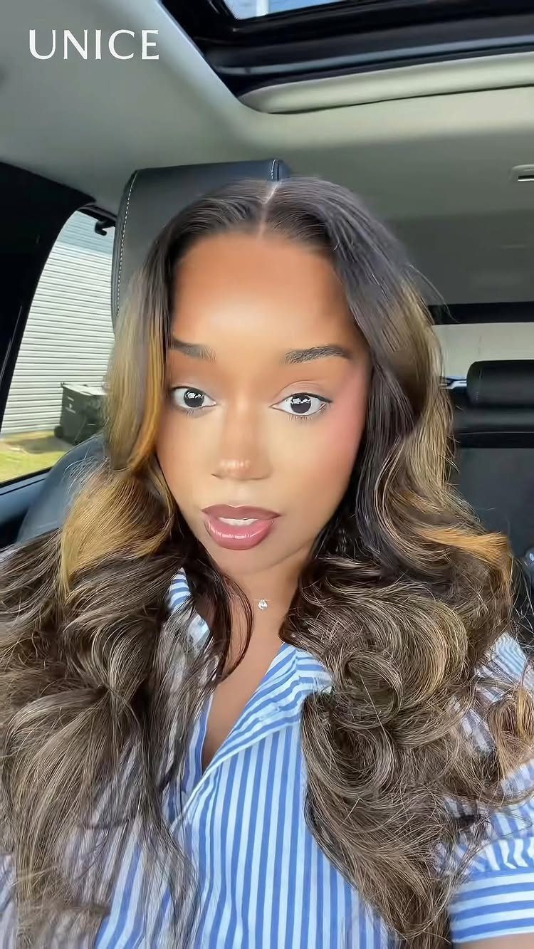 Woman displaying long dark hair with warm golden-brown highlights in a car