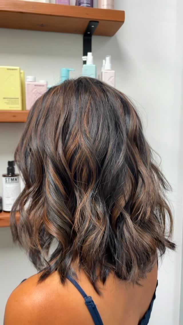 Wavy dark hair with subtle cool brown highlights at a salon