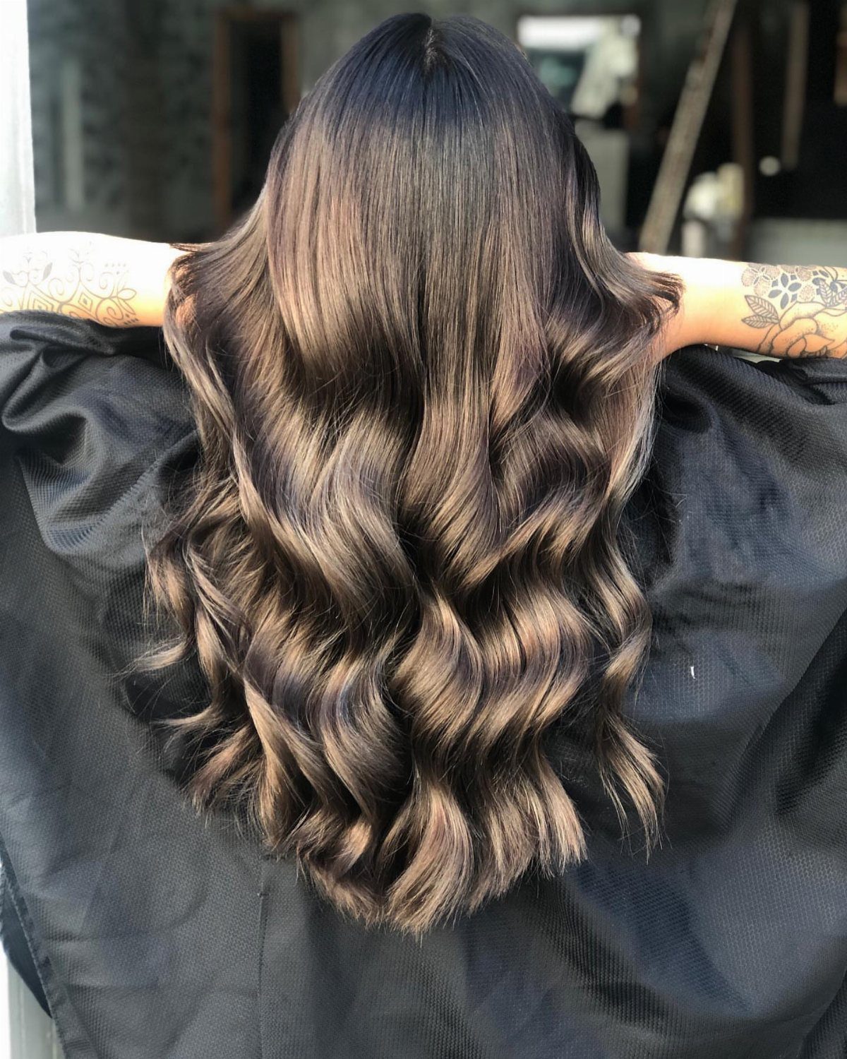 Long dark brown waves with warm almond-brown highlights in a salon