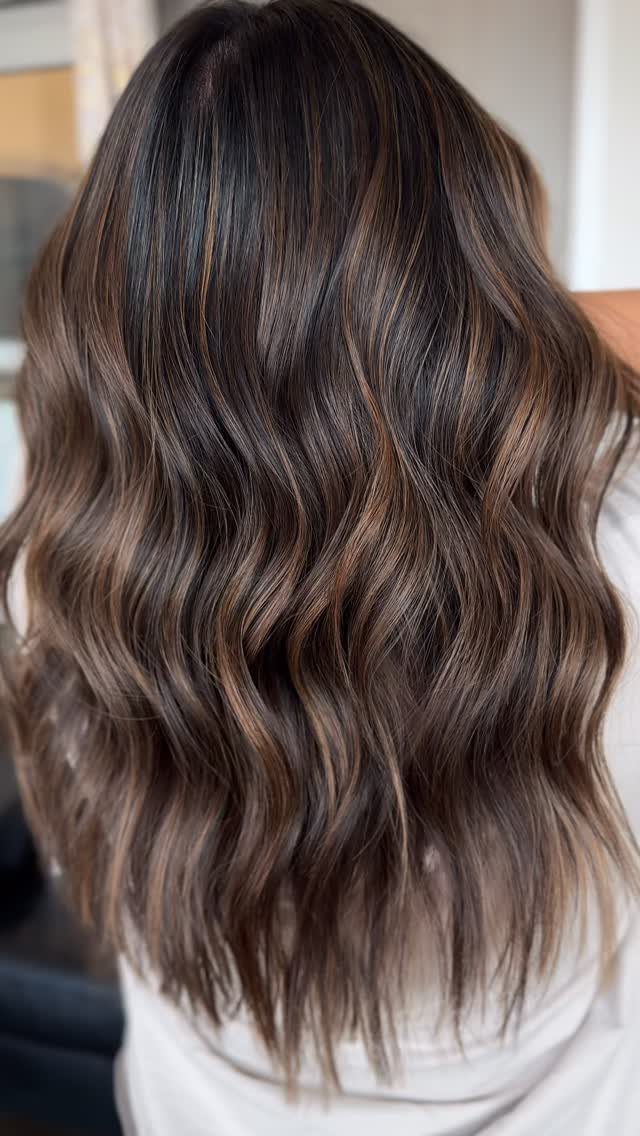 Long wavy dark hair shows fine, natural-looking brown highlight ribbons